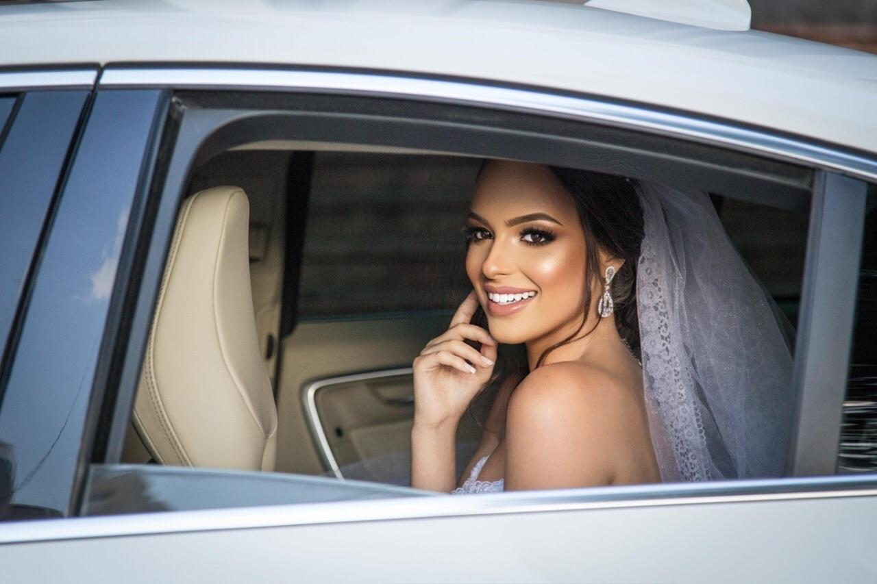 Noiva sorrindo na janela do carro, a caminho da cerimônia
